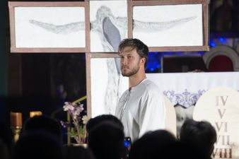 Mężczyzna ubrany na biały uosobiający Jezusa Chrystusa, z boku tablica z dekalogiem, z tle tablice składające się na krzyż, z przodu widownia