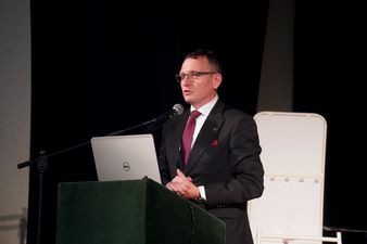Prezydent Michał Urgoł w czarnym garniturze przemawia ze sceny