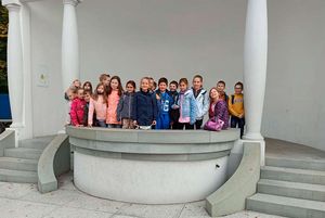 Uczniowie pozują do zdjęcia przy muszli koncertowej.