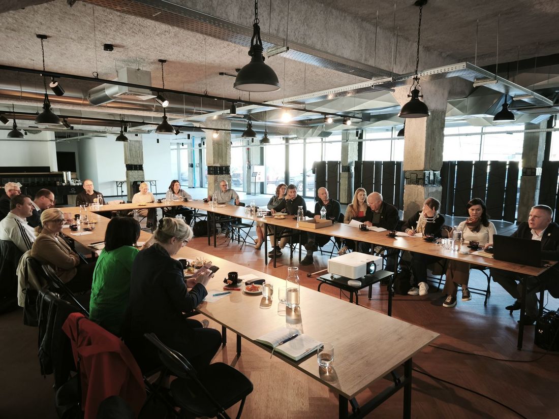 Uczestnicy spotkania siedzą przy stole, ujęcie szerokie