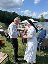 męzczyzna wrzuca datek do puszki trzymanej przez siostrę zakonną