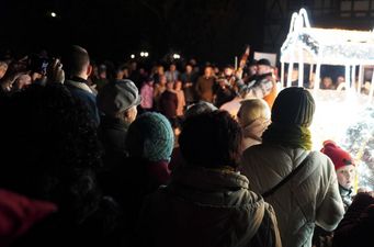Publiczność oglądająca zza pleców nocny występ kapeli grającej na instrumentach przy jasnej iluminacji