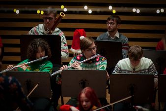Muzycy w świątecznych strojach grający na fletach, z tyłu mężczyzna z fagotem 