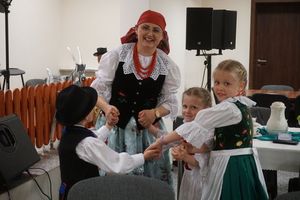 dzieci w strojach ludowych tańczące w kółku wraz z animatorką