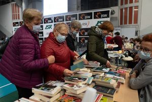 Osoby przy stoisku biblioteki, oglądają książki.