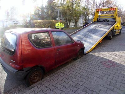 Czerwony wrak samochodu wciągany na lawetę