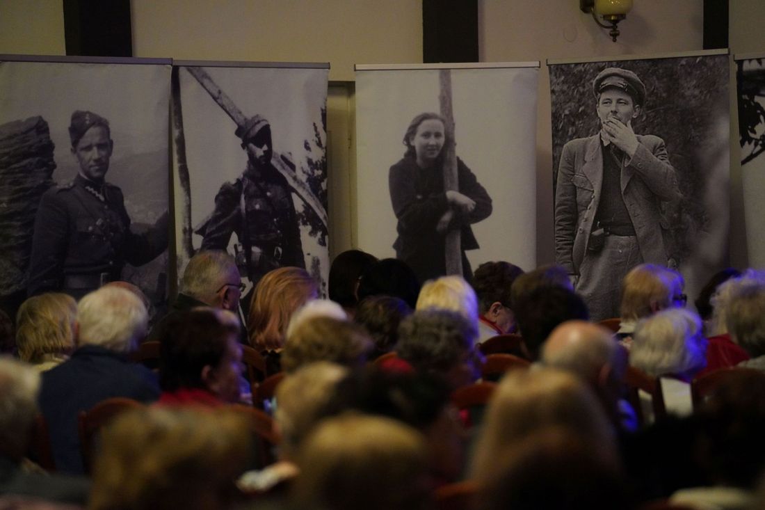 Na pierwszym planie bannery z wizerunkami kobiety i mężczyzn w szeregach żołnierzy wyklętych