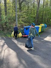 Osoby idące z workami śmieci do kontenerów