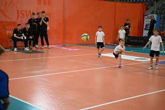 gra drużyna w białych koszulkach, chłopiec wykonał rzut w tle widać sędziów w czarnych strojach