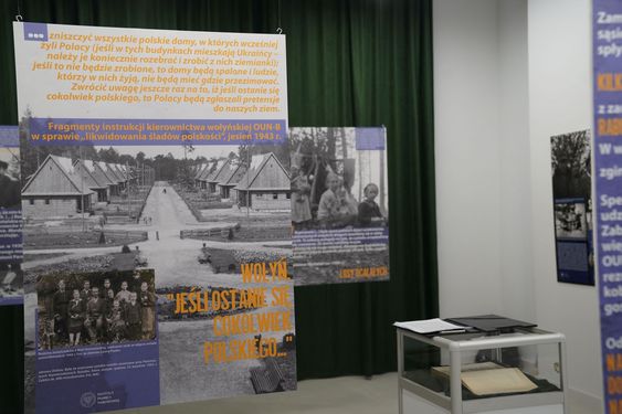 Plansza wystawowa z cytatem z instrukcji OUN-B oraz dużym, archiwalnym zdjęciem rzędu wiejskich domów