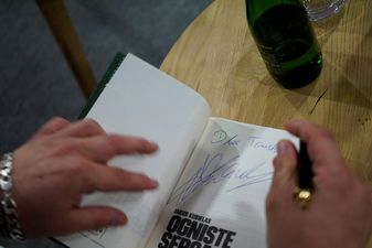 autor składa autograf na stronie tytułowej swojej książki