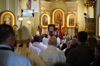 Duchowni i inni wierni stojący przodem do ołtarza, modląc się.