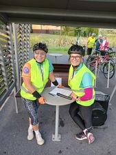 Dwie kobiety w rowerowych kaskach stoją przy stoliku