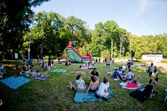 Panorama pikniku klubowego na Kąpielisku Zdrój; uczestnicy na kocach, w tle duży dmuchany zamek