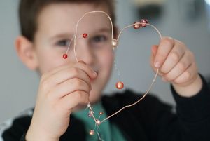 Chłopiec pokazujący serce z koralików