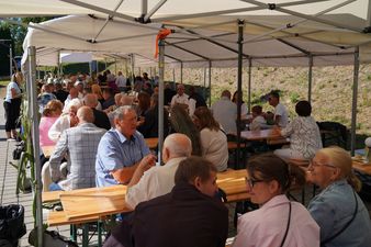 Duża grupa ludzi siedzących przy stołach ustawionych pod namiotem