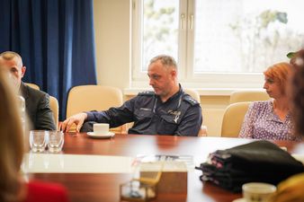 Przedstawiciel Policji siedzący przy stole słucha innych rozmówców 