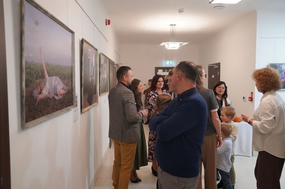 Odwiedzający rozmawiają w galerii sztuki, oglądając obrazy wiszące na jasnej ścianie