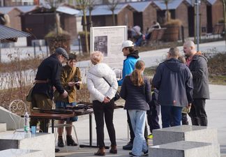 Grupka osób zgromadzona wokół stolika z zabytkową bronią