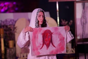 Kobieta ubrana na biało trzyma namalowany wizerunek Jezusa Chrystusa