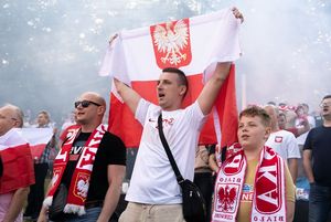 Kibice śpiewają hymn. W górze powiewa flaga.