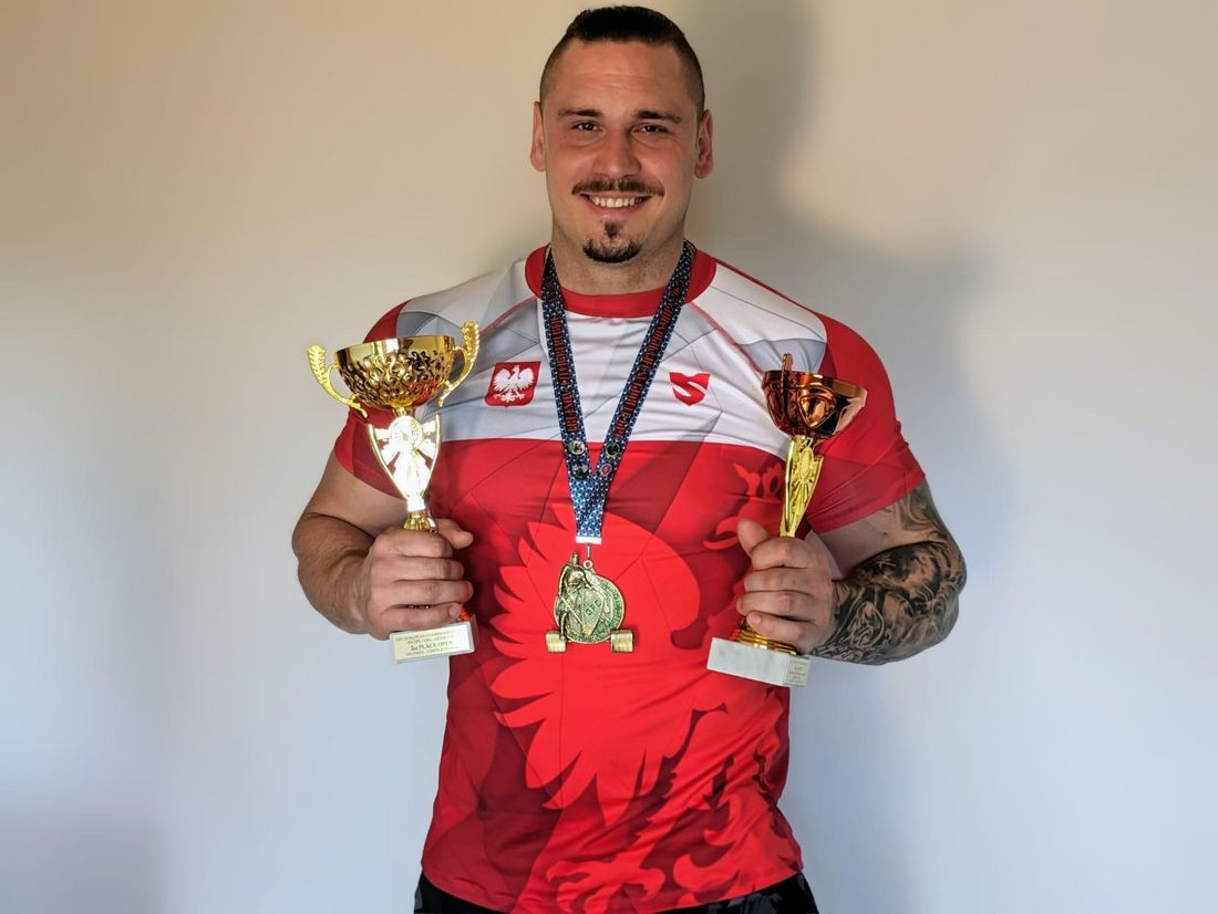 Dennis Sitek z dwoma pucharami w rękach i z medalem na szyi