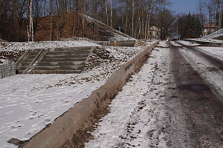 Drogowy mur oporowy i betonowe schody prowadzące w górę ośnieżonego zbocza
