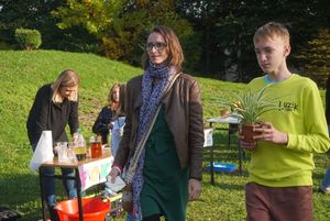 Uczestnicy pikniku, niosący roślinę z akcji adopcji roślin