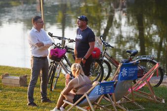 Michał Urgoł Prezydent Miasta podczas rozmowy z mieszkańcem na trawiastym brzegu obok rowerów i kobiety siedzącej na leżaku plażowym