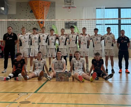 Pozująca na tle siatki drużyna Akademii Talentów z trenerami