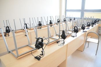 Pusta sala zajęciowa, na pierwszym planie ppuste ławki i krzesełka założone na stoliki