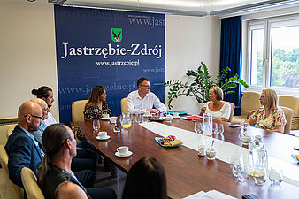 Prezydent Miasta wraz ze wszystkimi gośćmi siedzą przy stole i rozmawiają. 