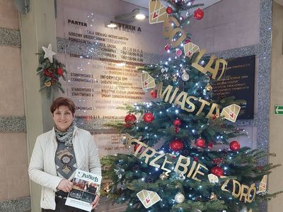 Autorka na tle ozdobionej choinki w urzedzie miasta trzymająca w dłoni gazetę jastrząb