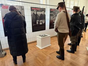 Wystawa na temat Inki, przed tablicami ludzie w strojach partyzantów, na ramionach mają przewieszoną zabytkową broń