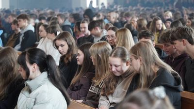 Młodzież siedząca w ławkach w kościele, oczekująca na rekolekcje.