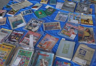 Stare czasopisma (m.in. Przegląd Sportowy, Historia) oraz komiksy ułożone na niebieskiej plandece rozłożonej na ziemi