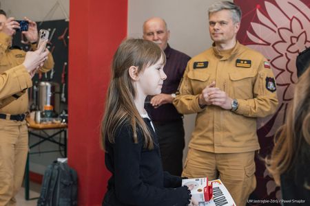 Dziewczynka zmierza w stronę oficjeli wręczających nagrody