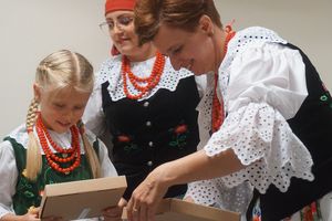Kobiety z koła gopodyń wiejskich w strojach ludowych wręczają dziewczynce prezent