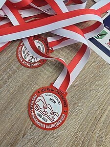 Pamiątkowy medal sztafety pływackiej z biało-czerwoną wstążką leżący na drewnianym stole