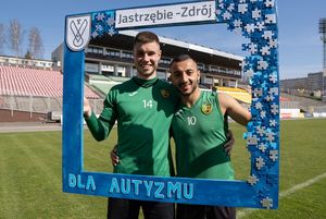 Piłkarze GKS Jastrzębie trzymają drewnianą, niebieską ramkę z napisem "dla autyzmu"