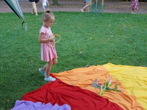 Dziewczynka w różowej sukience przygotowuje się do rzutu liny w grze zręcznościowej na kolorowej macie w parku.