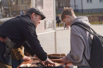 Młody chłopak otrzymuje instrukcje z rąk organizatora gry terenowej