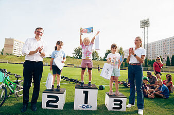 Dziewczynka na pierwszym miejscu podium wznosi puchar