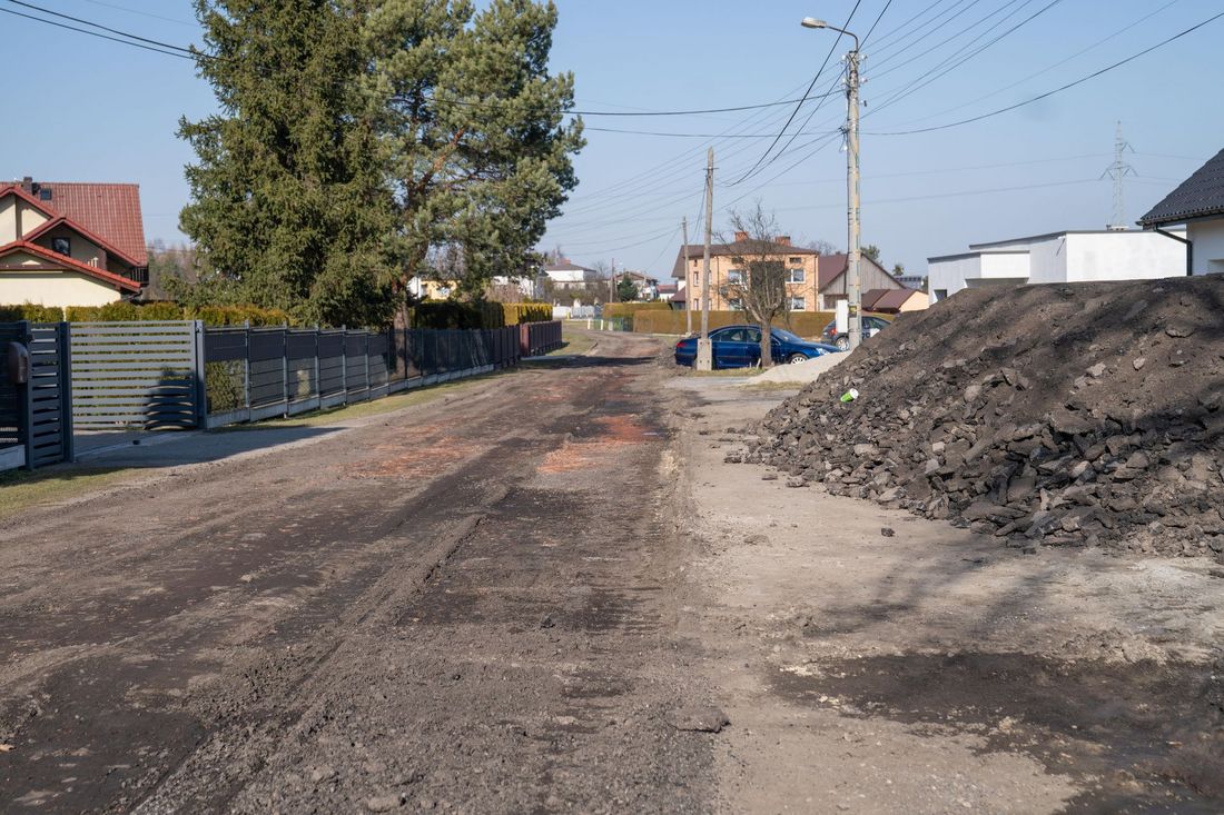 Remontowana ulica bez ze zdartą powierzchnią, obok sterta gruzu i ziemi 