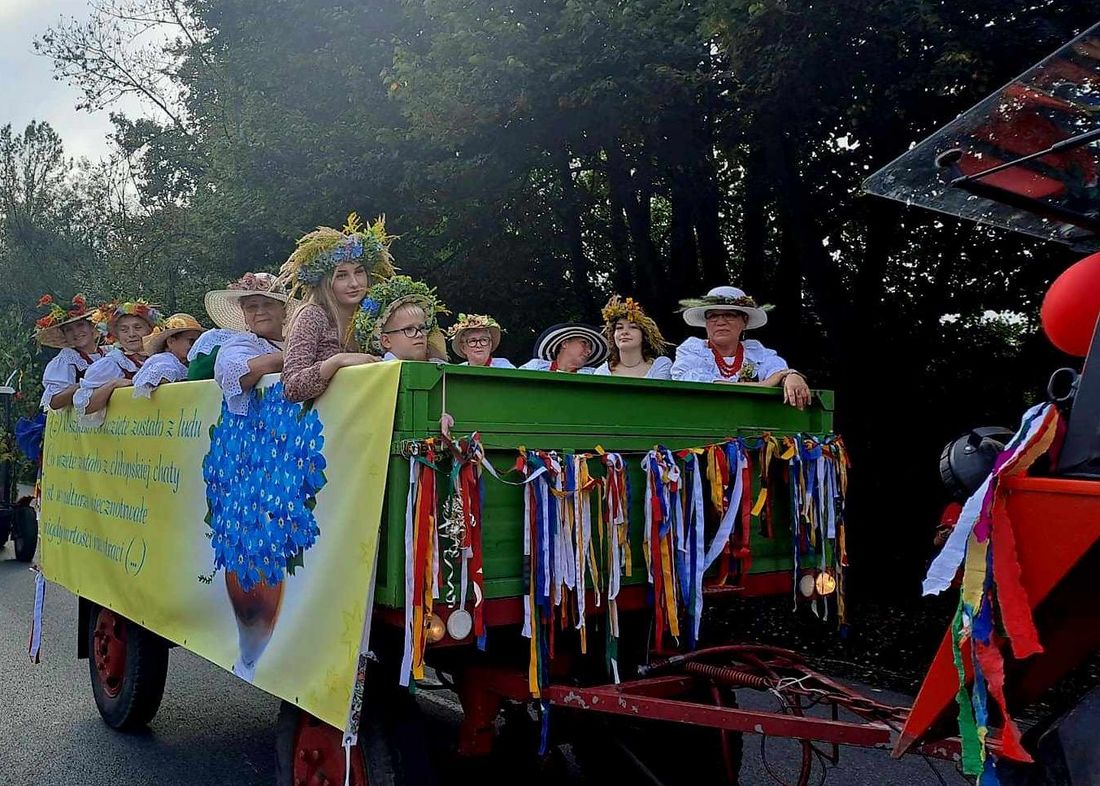 Zdjęcie przedstawia ludzi na wozie podczas dożynek