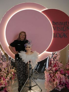 Monika Bierska pozuje na różowym tle trzymając główkę treningową ze zwycięską fryzurą