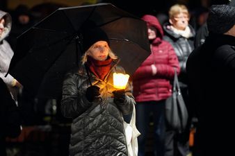 Kobieta pod parasolem trzyma w ręku zapalony lampion