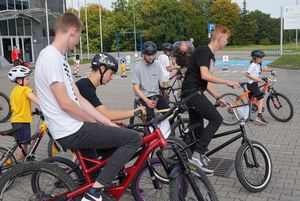 Grupa rowerzystów przed halą widowiskowo-sportową