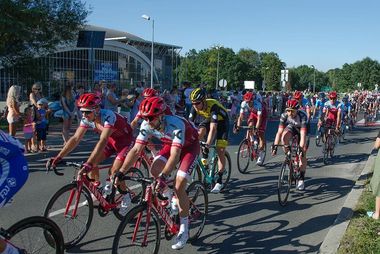 Peleton kolarzy Tour de pologne pod halą widowiskowo-sportową