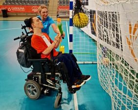 Zawodnik trafiający kijem sportowym w piłkę zawieszona na bramce